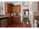 Kitchen with stainless steel appliances, wood cabinets, and hardwood flooring leading to the dining area at 7562 Sedgebrook W Dr, Stanley, NC 28164