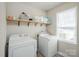 Functional laundry room with washer, dryer, and open shelving for organized storage at 9613 Central Dr, Mint Hill, NC 28227