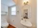 Well-lit half-bath with pedestal sink, updated fixtures, and a mirror at 9684 Ravenscroft Nw Ln, Concord, NC 28027