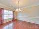 Traditional dining room boasts hardwood floors, elegant chandelier, and natural light from the large window at 9684 Ravenscroft Nw Ln, Concord, NC 28027