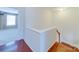 Hallway showcasing hardwood floors, a staircase, and a view of the bright bedroom at 9684 Ravenscroft Nw Ln, Concord, NC 28027