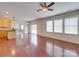 Spacious living room with hardwood floors, a ceiling fan, and natural light streaming through the windows at 9684 Ravenscroft Nw Ln, Concord, NC 28027