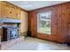 Living room with a brick fireplace, wood paneled walls, and a large window at 1109 Hemlock Dr, Shelby, NC 28150