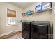 Functional laundry room with modern washer and dryer, shelving for storage and a bright window at 11122 Windgate Ct, Tega Cay, SC 29708