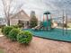 Community playground with green mulch, slide, and climbing structure with clubhouse visible in the background at 12432 Bradford Park Dr, Davidson, NC 28036