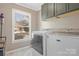 Bright laundry room with a window, modern washer and dryer set, and overhead cabinets for ample storage space at 1417 Shady Bark Dr, Gastonia, NC 28054