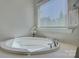 Bathroom featuring a bright soaking tub next to a window with white trim at 17809 Pawleys Plantation Ln, Charlotte, NC 28278