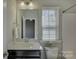 Bright bathroom with a single sink vanity, a large mirror, and a window providing natural light at 17809 Pawleys Plantation Ln, Charlotte, NC 28278