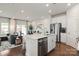 Modern kitchen with stainless steel appliances, white cabinetry, and a breakfast bar, seamlessly connected to the living area at 2080 Old Rivers Rd, Concord, NC 28027