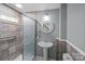 Bathroom featuring shower, pedestal sink, round mirror and tiled walls at 220 W Bell St, Statesville, NC 28677