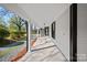 Long front porch with painted wood floors, bright white columns, and partial views of the surrounding lawn at 220 W Bell St, Statesville, NC 28677