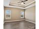 Large bedroom with a tray ceiling, natural light, and neutral tones at 6420 Cambridge Dr, Harrisburg, NC 28075