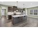 Modern kitchen features an island with pendant lighting, dark cabinetry, and stainless steel appliances at 6420 Cambridge Dr, Harrisburg, NC 28075