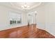 Bright dining room with hardwood floors, white wainscoting, tray ceiling, and large windows at 1017 Anduin Falls Dr, Charlotte, NC 28269