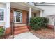 Charming front porch with brick steps, decorative railing, and a manicured shrub at 1017 Anduin Falls Dr, Charlotte, NC 28269