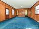 Spacious living room featuring wood paneled walls, blue carpet and built-in bookshelves at 1030 Bolling Rd, Charlotte, NC 28207