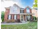 Charming two-story brick home with a manicured lawn, rocking chairs on the front porch, and black shutters at 10836 Clark St, Davidson, NC 28036