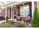 Cozy front porch with rocking chairs, complemented by well-maintained landscaping and classic brickwork at 10836 Clark St, Davidson, NC 28036