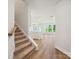Bright hallway leading to an open kitchen and living area with wood-look floors and carpeted staircase at 109 Alluvium Ln, Waxhaw, NC 28173