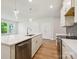 Modern kitchen with stainless steel dishwasher, large island, and wood-look flooring at 109 Alluvium Ln, Waxhaw, NC 28173
