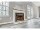 Traditional living room fireplace with white mantle, wood-look flooring, and French doors at 1107 Franklin Thomas Pl, Charlotte, NC 28214