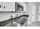 Close-up of updated electric range with black countertop and white cabinetry above at 1107 Franklin Thomas Pl, Charlotte, NC 28214