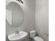 Powder room with a toilet and floating sink with round mirror at 13923 Singleleaf Ln, Charlotte, NC 28278