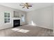 Cozy living room with a fireplace, ceiling fan, and carpeted floors at 13923 Singleleaf Ln, Charlotte, NC 28278