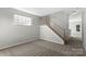 Spacious living room with neutral carpet, staircase, and large window for plenty of natural light at 13923 Singleleaf Ln, Charlotte, NC 28278