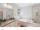 This main bathroom features a separate shower, granite vanity and a garden tub beneath a window at 14621 Brannock Hills Dr, Charlotte, NC 28278