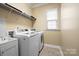 Practical laundry room with modern washer, dryer, shelving, and built-in sink at 16023 Rushwick Dr, Huntersville, NC 28078