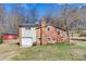 A two-story home featuring a brick and vinyl exterior, a one-car garage, and a red barn, set in a grassy area at 1740 Young Dr, Conover, NC 28613