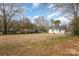 View of a large backyard with a basketball hoop, mature trees, and the back of a home with a patio at 201 Wiley Ave, York, SC 29745