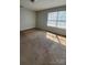 A bedroom with light-colored walls and carpet, with large window letting in sunlight at 2108 Cranberry Woods Ct, Charlotte, NC 28208