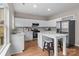 Bright kitchen featuring white cabinets, stainless steel appliances, island with seating, and hardwood floors at 302 Flanders Dr, Mooresville, NC 28117