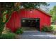 A bright red storage building with a garage door features ample storage, set in a landscaped yard with lush greenery at 7271 Hallman Mill Rd, Vale, NC 28168