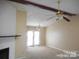 Bright living room with a ceiling fan, wood beam, stone fireplace, and natural light pouring through double doors at 8319 Golf Ridge Dr, Charlotte, NC 28277