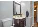 Half bathroom with a decorative mirror, dark vanity, and white toilet at 916 Somersby Ln, Matthews, NC 28105