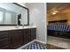 Bathroom with a large mirror, dark cabinets, white counter, and blue and white accent rug, and view into Primary bedroom at 916 Somersby Ln, Matthews, NC 28105