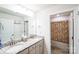 Bathroom with dual sinks, granite counters, white cabinets, and a framed mirror at 9300 Vecchio Dr, Indian Land, SC 29707