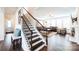 Staircase with stained wood treads and handrail leading into a living area with large windows at 9300 Vecchio Dr, Indian Land, SC 29707