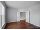 A simple, empty bedroom features hardwood floors, a large window, and an adjoining closet at 1009 Rocky Meadows Ln, Concord, NC 28025