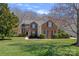 Charming two-story brick home featuring a manicured lawn, lush landscaping, and classic architectural details at 1161 Woodwinds Dr, Waxhaw, NC 28173