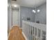 Upstairs hallway with wood floors, neutral gray walls, white trim, and chandelier at 12928 Sickles Dr, Charlotte, NC 28273