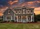 Two-story home showcasing its covered front porch with classic columns under a sunset-colored sky at 142 Tuscany Trl, Mooresville, NC 28117