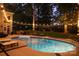 Outdoor pool with lounge chairs and an outdoor kitchen area under string lights at 17048 Jetton Rd, Cornelius, NC 28031