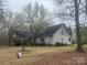 A traditional home with gray vinyl siding and a rear deck, nestled among mature trees and a spacious backyard at 2025 Sojourn Rd, Marshville, NC 28103