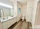 Bright bathroom showcasing double sink vanity with modern fixtures, new floors, toilet, and a door to a closet or bedroom at 2025 Sojourn Rd, Marshville, NC 28103