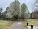 Long gravel driveway leading to a home lined with trees, adding natural beauty and seclusion to the property at 2025 Sojourn Rd, Marshville, NC 28103