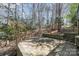 A stone-paved patio sits in the backyard surrounded by trees, bushes, and a stone staircase at 2320 Christensens Ct, Charlotte, NC 28270